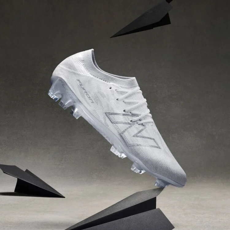 A bright yellow soccer cleat with black and red accents is displayed on its side among several glass prisms on a neutral gray surface.