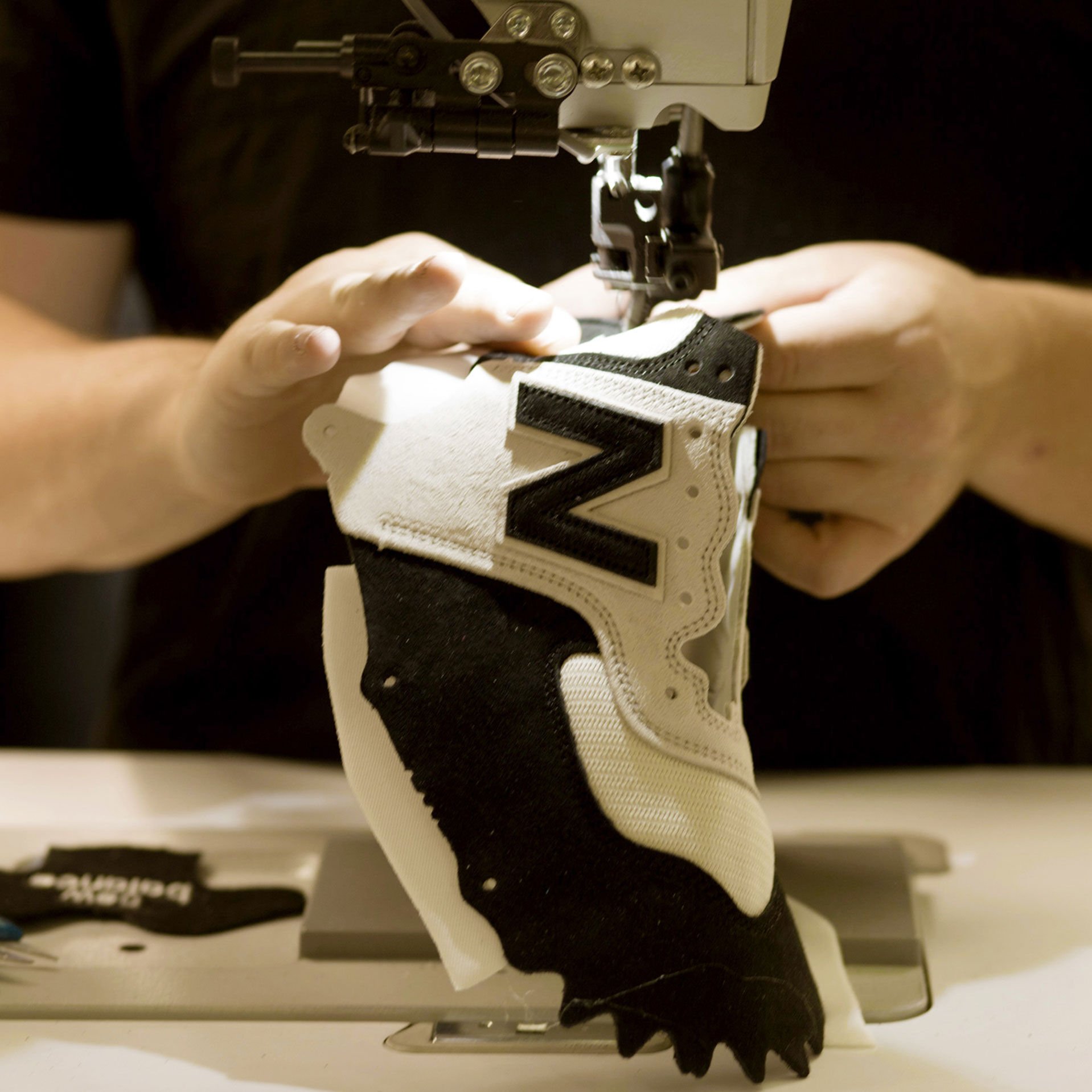 Factory worker stitching shoe