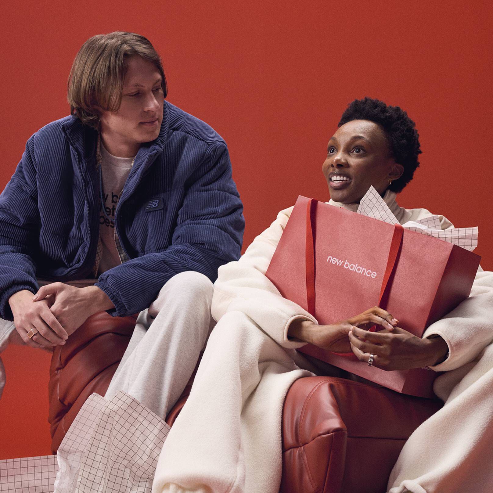A person holding a New Balance branded bag with anotherother person looking at them.