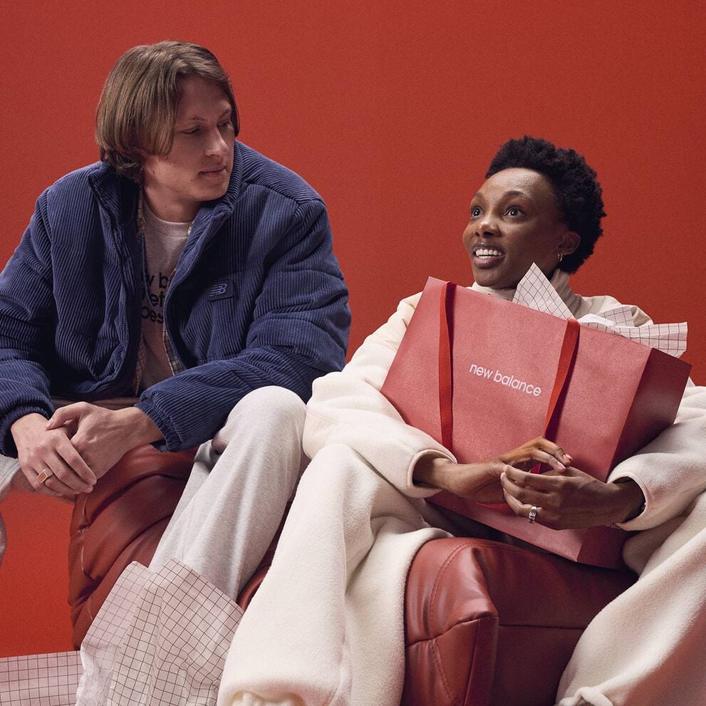 A person holding a New Balance branded bag with anotherother person looking at them.