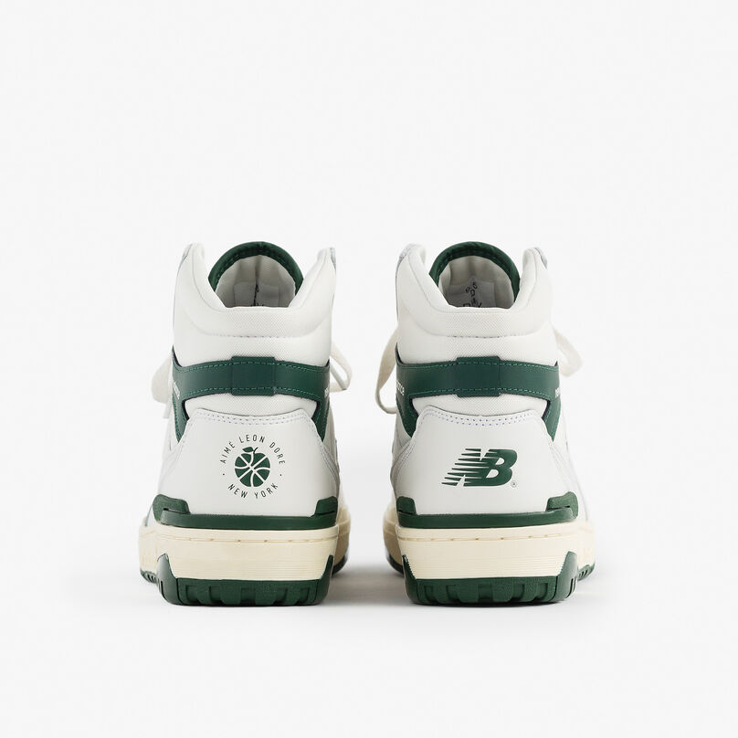 Pair of green and white 650 shoes shown from the back to displ Aimé Leon Dore and New Balance logos on the heel