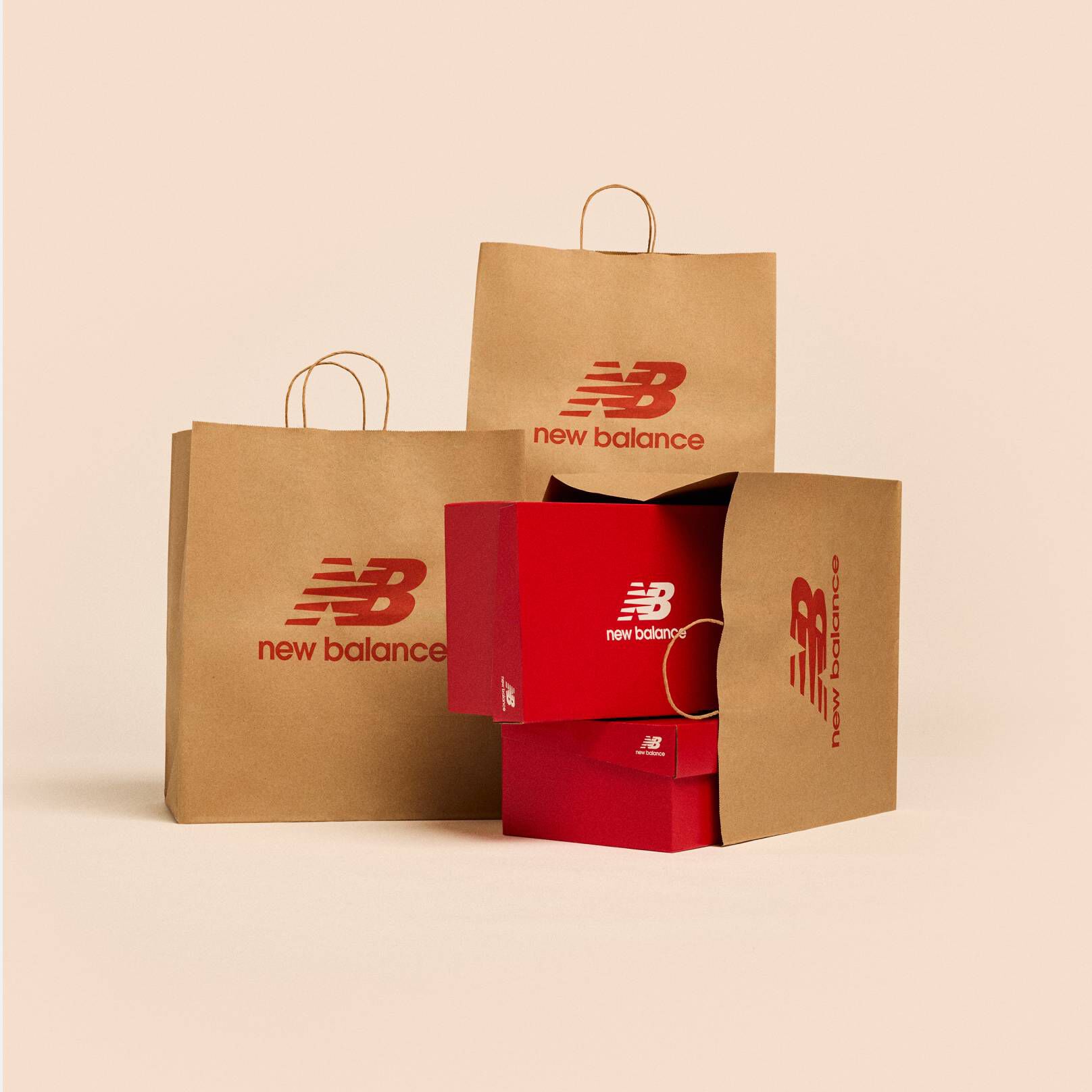 A group of New Balance branded bags and shoe boxes sitting on a beige background.
