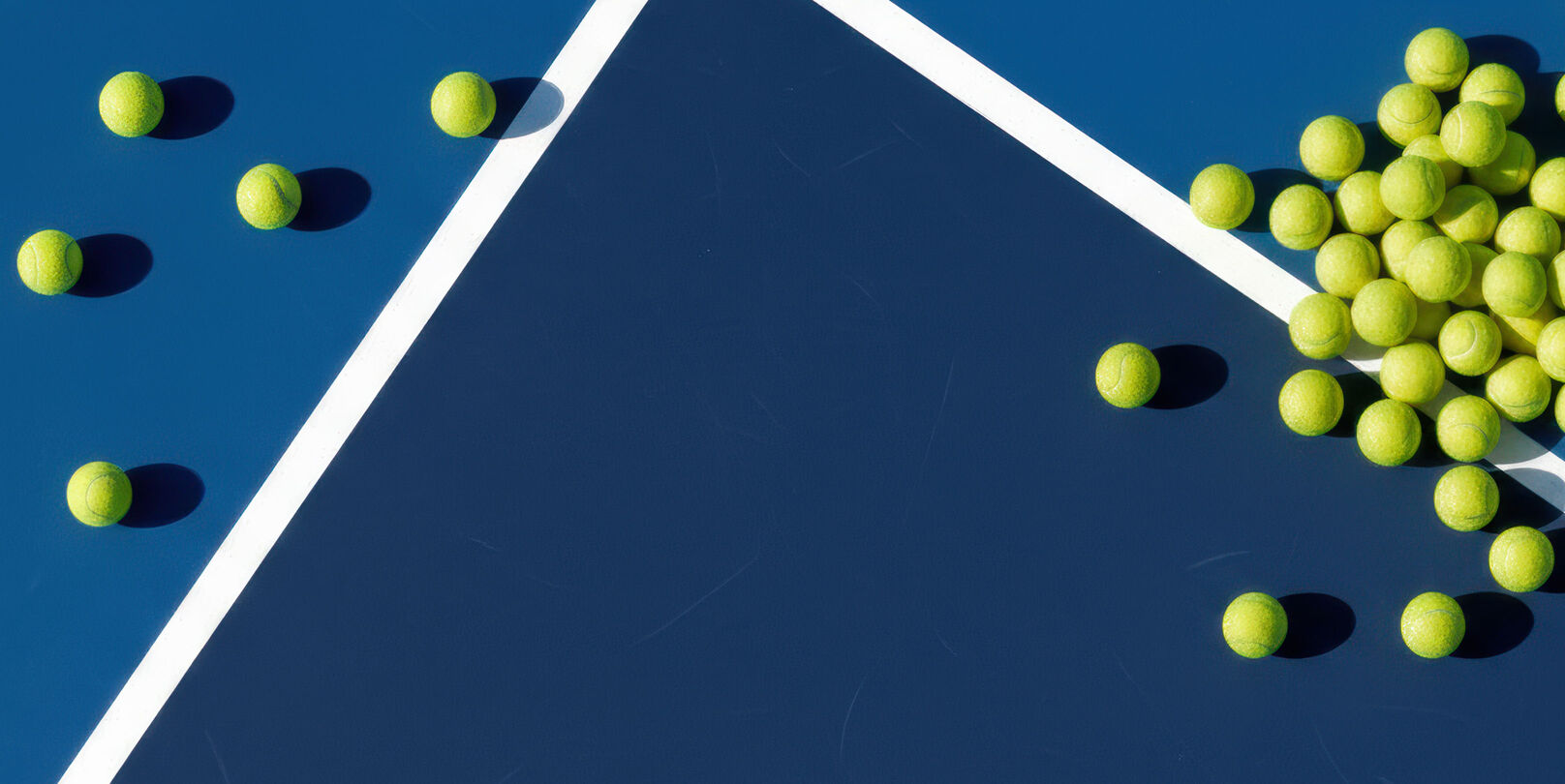 Tennis balls laying on a tennis court.