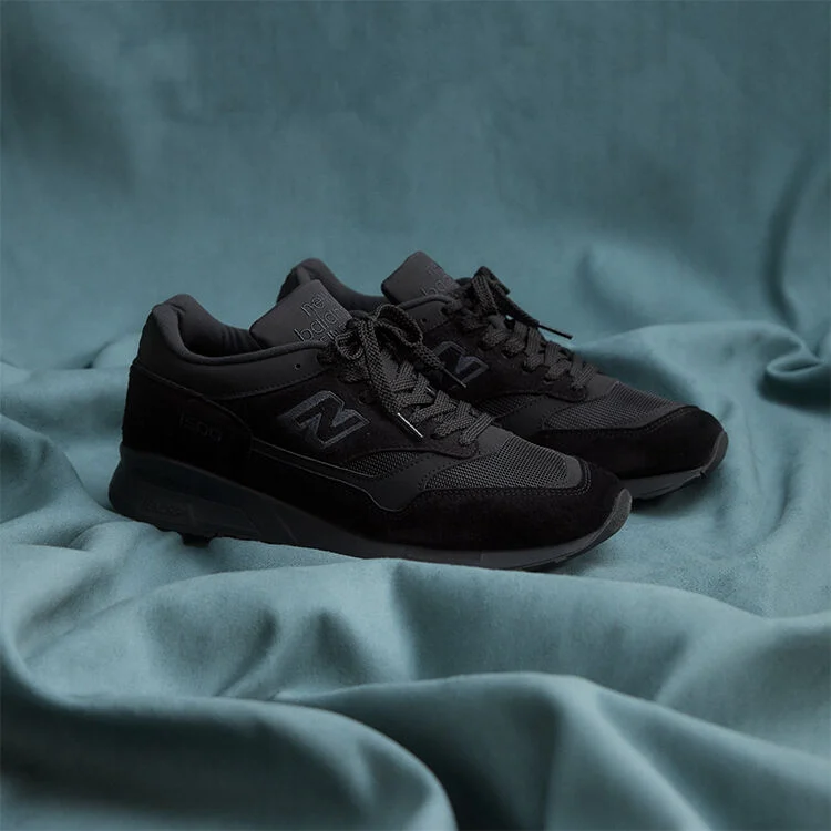 A pair of New Balance Made in UK sneakers on a flowing blue sheet backdrop.  
