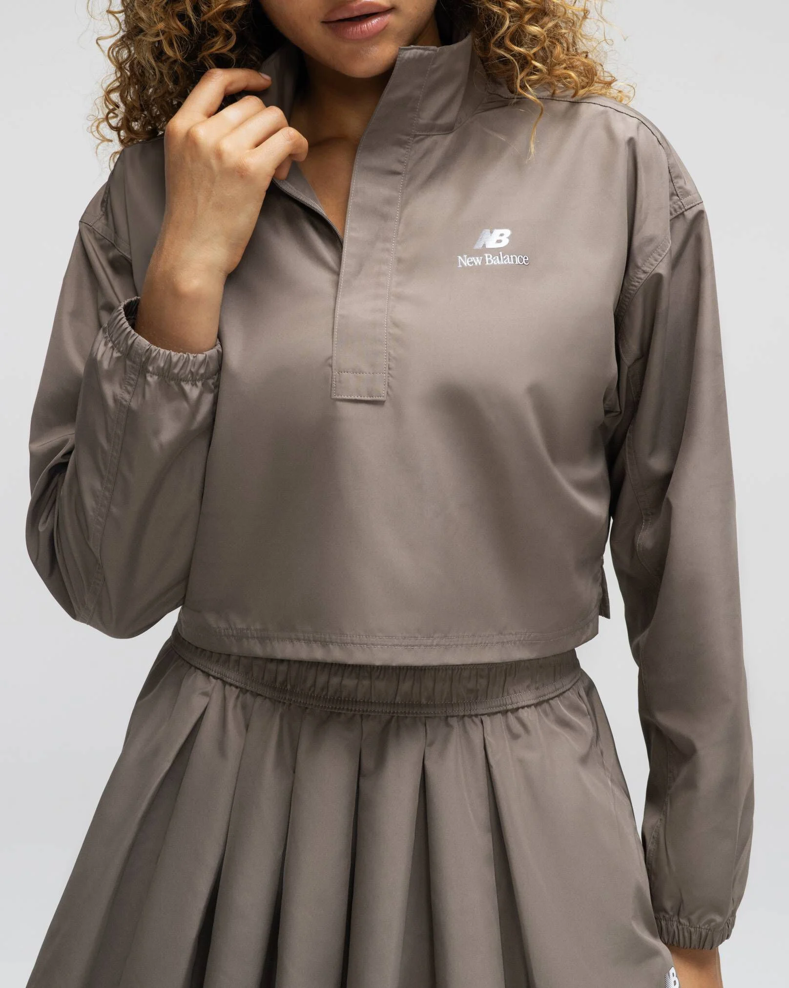 A woman wearing New Balance standing against a grey studio backdrop 