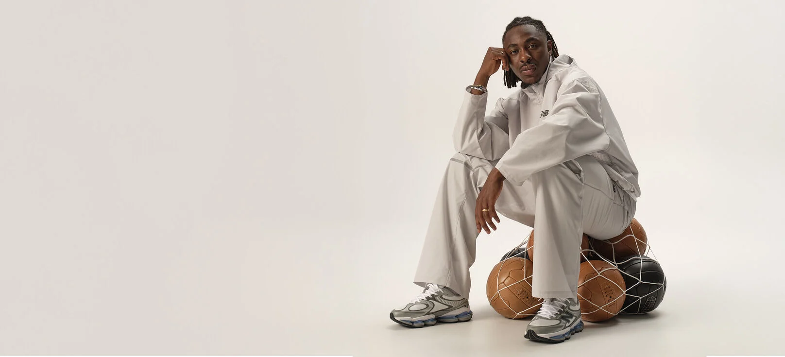 Football player Eberechi Eze sitting on footballs in studio. 