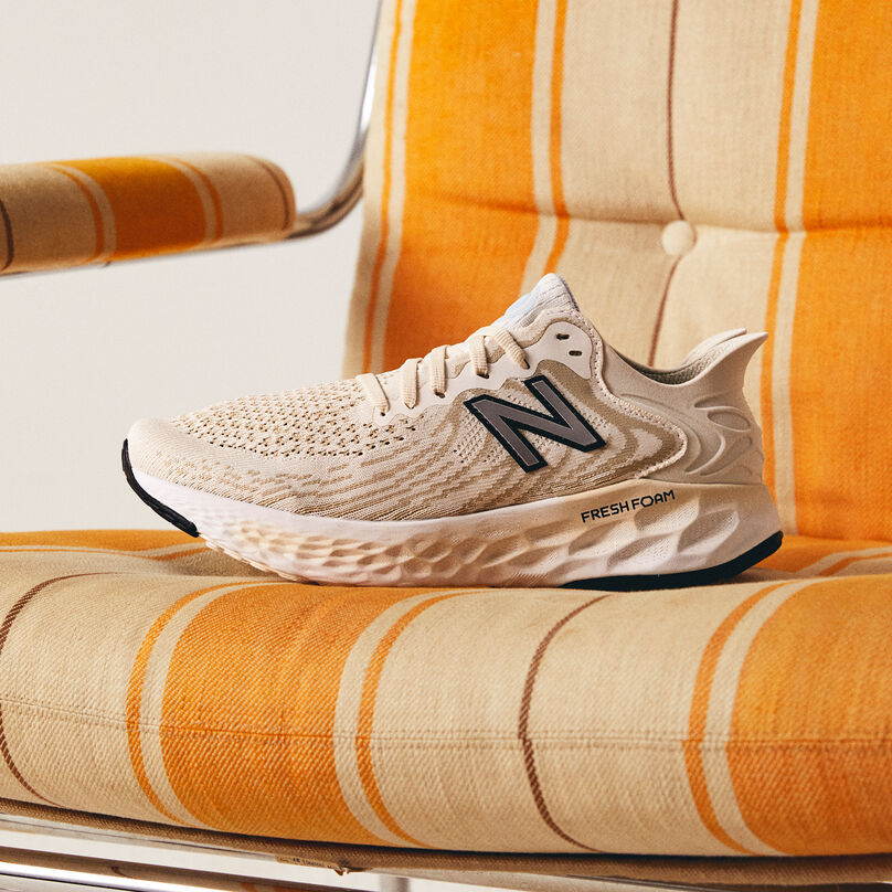 Single shoe sitting on an orange and off-white striped chair.