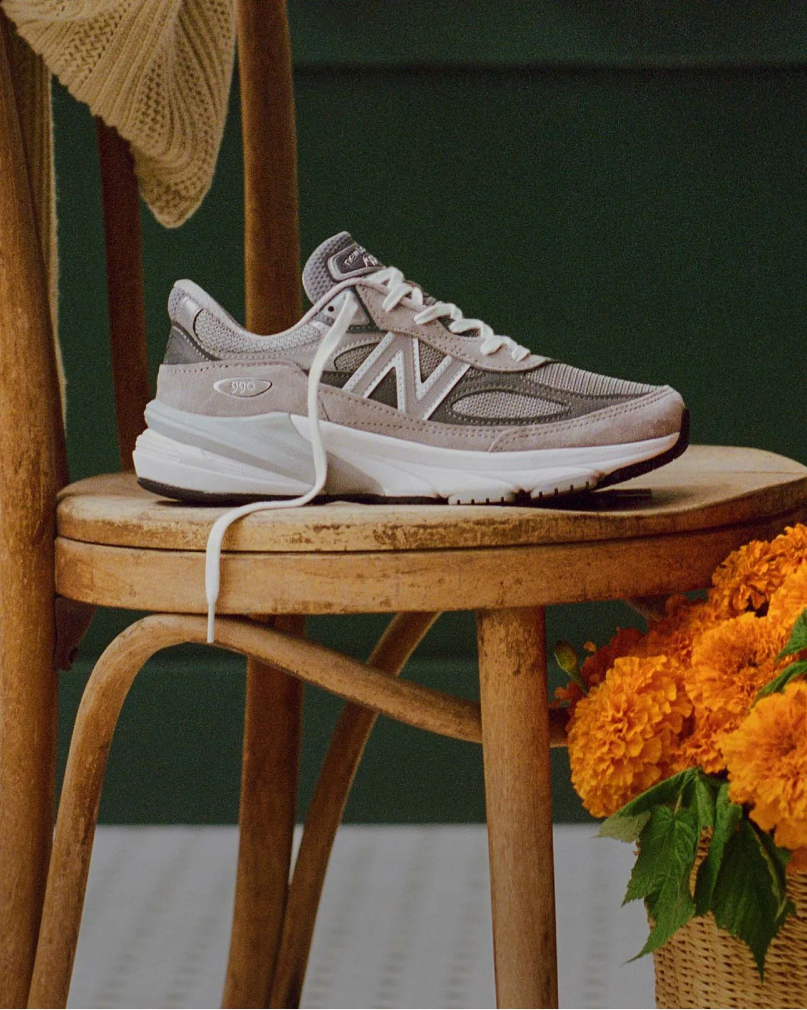 A grey 990v6 sneaker sitting on a chair in a cafe environment. 